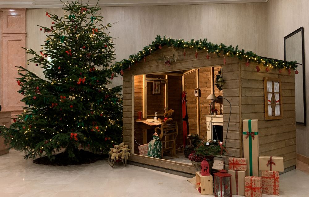 Versierde houten kerstchalet met kerstboom en cadeaus