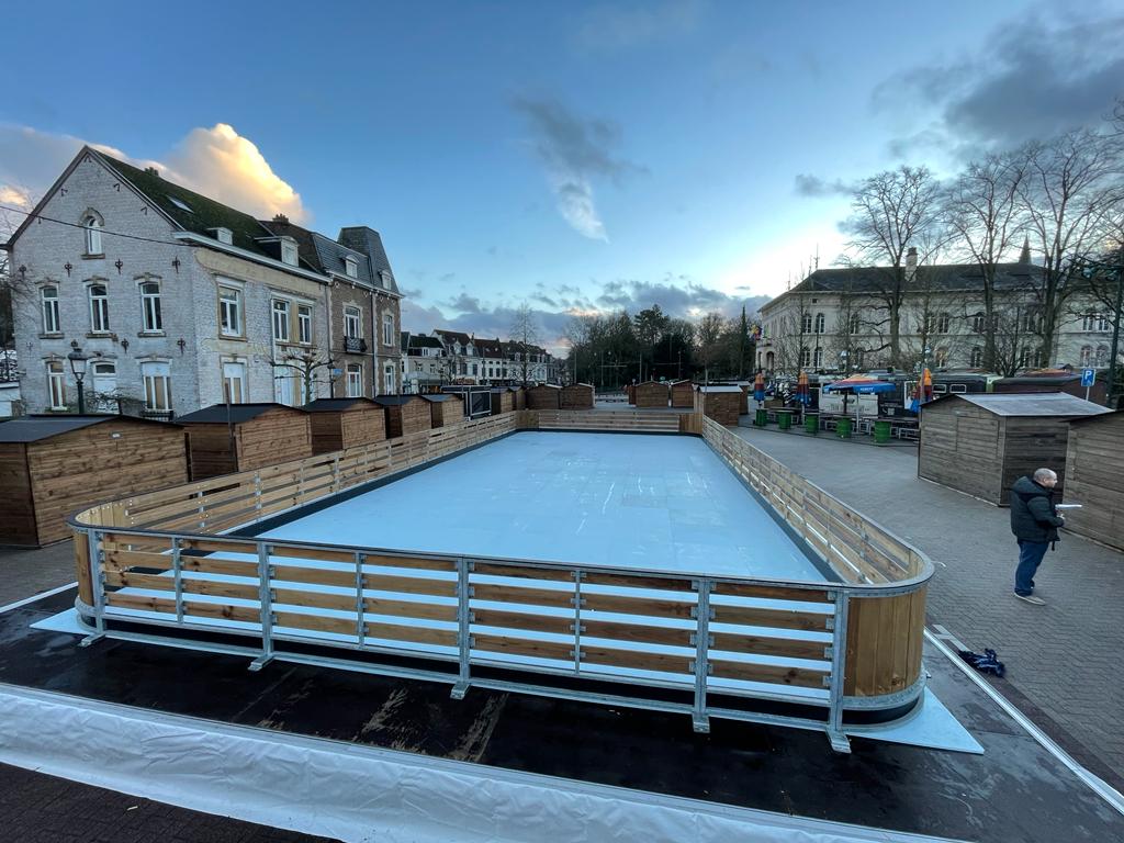 Kerstmarkt met schaatsbaan omringd door houten chalets
